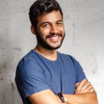 portrait photo of smiling man with his arms crossed standing in front of a wall